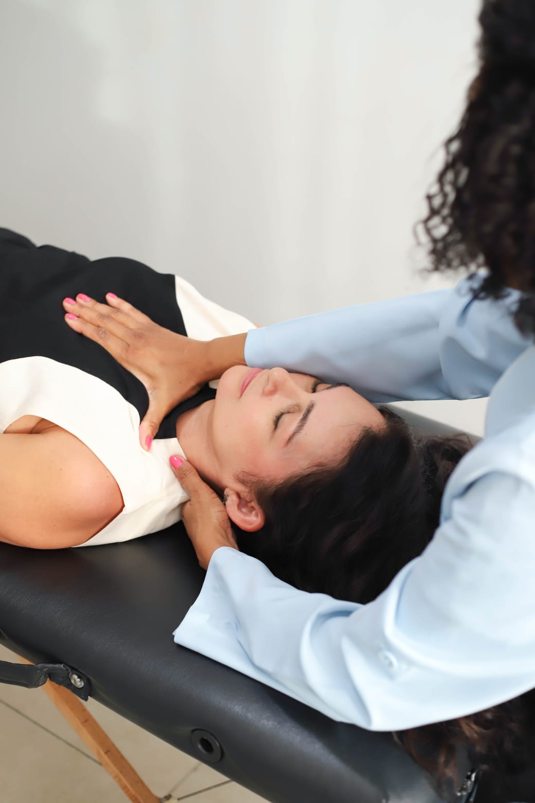 Dra. Iane realizando palpação cervical em paciente na maca